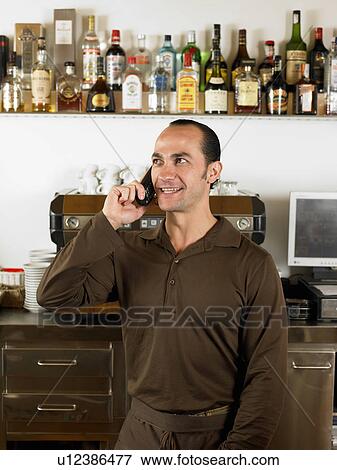 Bartender on the phone in front of coffee machine. View Large Photo Image Stock Photo - Bartender on the phone in front of coffee machine.. Fotosearch