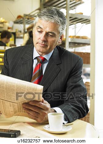 Mature businessman sitting in cafe reading financial newspaper View Large Photo Image Stock Photo - Mature businessman sitting in cafe reading financial newspaper. Fotosearch