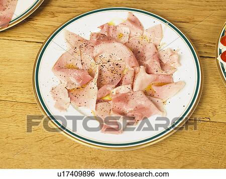 Stock Photograph - Plate of cured ham on table, close-up. Fotosearch