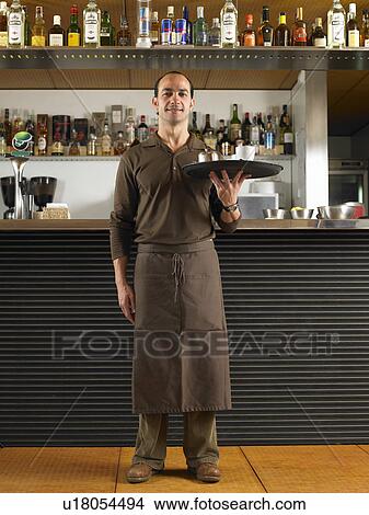 Waiter in long apron holding tray in front of bar. View Large Photo Image Picture - Waiter in long apron holding tray in front of bar.. Fotosearch