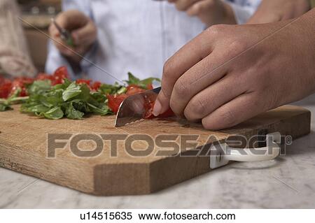 Stock Photography - Woman chopping tomato's on board, close-up. Fotosearch