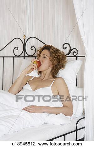 woman in bed biting apple View Large Photo Image Stock Image - woman in bed biting apple. Fotosearch