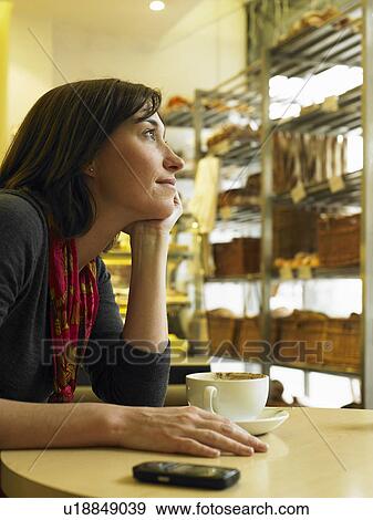 Stock Photo - Woman sitting in cafe resting chin on hand. Fotosearch