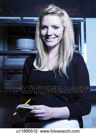 Young waitress holding notepad in kitchen, smiling, portrait View Large Photo Image Stock Image - Young waitress holding notepad in kitchen, smiling, portrait. Fotosearch