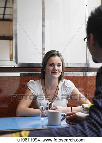 Picture - Young woman sitting in cafe with man, smiling. Fotosearch