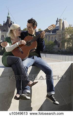 Couple playing guitar outdoors smiling. View Large Photo Image Stock Image - Couple playing guitar outdoors smiling.. Fotosearch