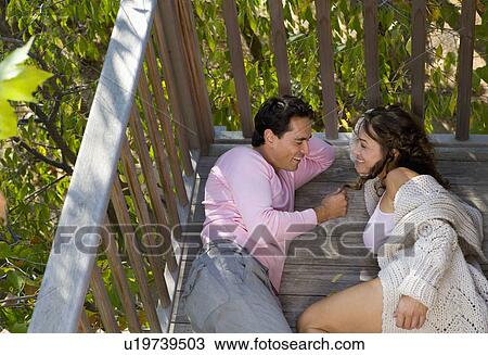 Stock Image - Couple relaxing outdoors smiling.. Fotosearch
