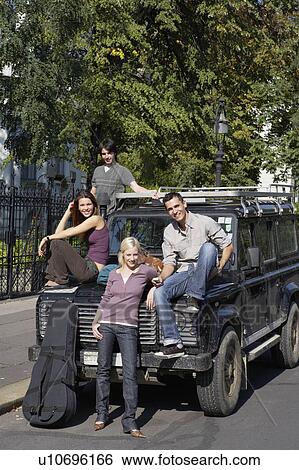 Four friends with an SUV and a guitar smiling. View Large Photo Image Stock Photograph - Four friends with an SUV and a guitar smiling.. Fotosearch