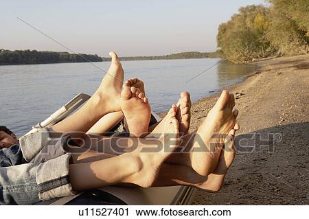 Four people's legs hanging over the edge of a raft. View Large Photo Image Stock Image - Four people's legs hanging over the edge of a raft.. Fotosearch