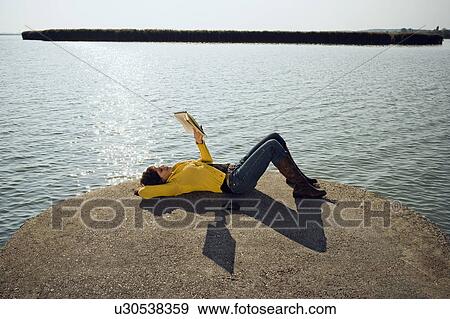 Stock Photo - Girl reading by lake.. Fotosearch