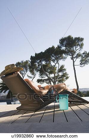Stock Image - Man lying on sun lounger.. Fotosearch