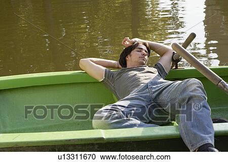 Stock Image - Man sleeping in a rowboat.. Fotosearch