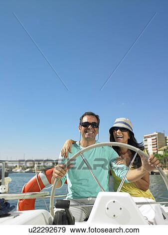 Mature couple wearing sunglasses at wheel of yacht, smiling View Large Photo Image Stock Photo - Mature couple wearing sunglasses at wheel of yacht, smiling. Fotosearch