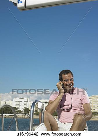 Mature man sitting on yacht using mobile phone, smiling View Large Photo Image Stock Image - Mature man sitting on yacht using mobile phone, smiling. Fotosearch