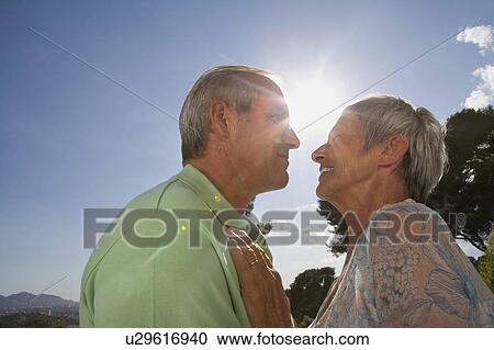 Stock Image - Older couple hugging on terrace.. Fotosearch