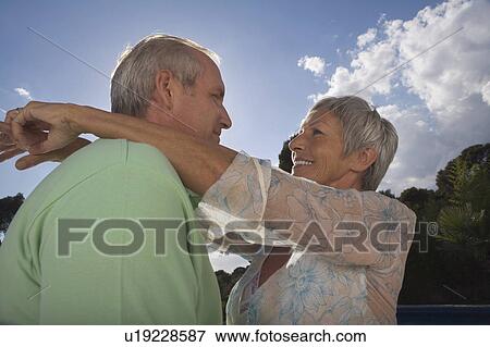 Stock Photo - Older couple hugging on terrace.. Fotosearch