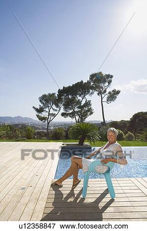 Older woman relaxing by a pool. View Large Photo Image Stock Photo - Older woman relaxing by a pool.. Fotosearch