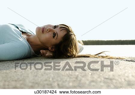 Picture - Portrait of woman lying by lake.. Fotosearch