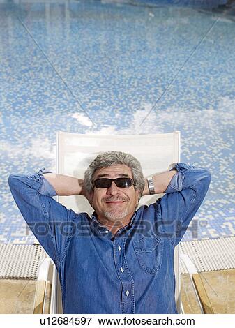 Stock Photo - Senior man wearing sunglasses relaxing in deckchair. Fotosearch