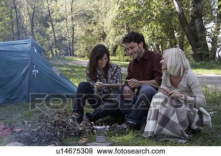 Three people at campsite cooking hot dogs and smiling. View Large Photo Image Stock Photo - Three people at campsite cooking hot dogs and smiling.. Fotosearch