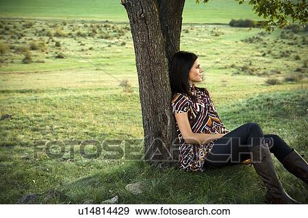 Stock Photo - Woman leaning against tree.. Fotosearch