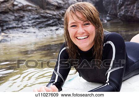 Woman lying on surfboard in the water laughing. View Large Photo Image Stock Photo - Woman lying on surfboard in the water laughing.. Fotosearch