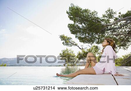 Woman relaxing by infinity pool. View Large Photo Image Picture - Woman relaxing by infinity pool.. Fotosearch