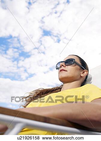 Woman wearing sunglasses relaxing in chair View Large Photo Image Stock Photo - Woman wearing sunglasses relaxing in chair. Fotosearch