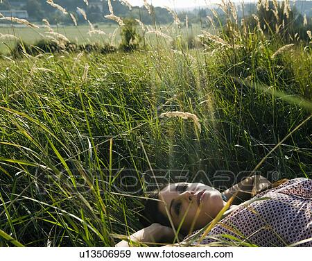 Stock Photo - Young woman lying in grass.. Fotosearch