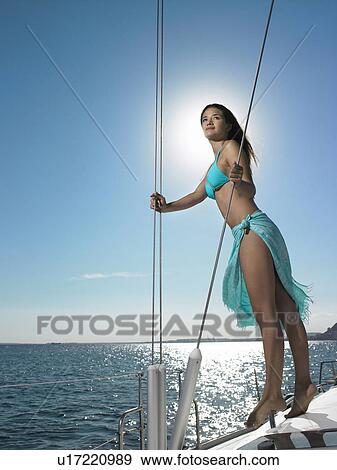 Stock Photo - Young woman standing on yacht at sea. Fotosearch