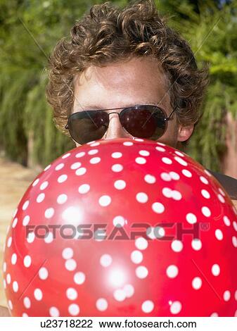 Man blowing up a balloon and wearing sunglasses. View Large Photo Image Stock Image - Man blowing up a balloon and wearing sunglasses.. Fotosearch