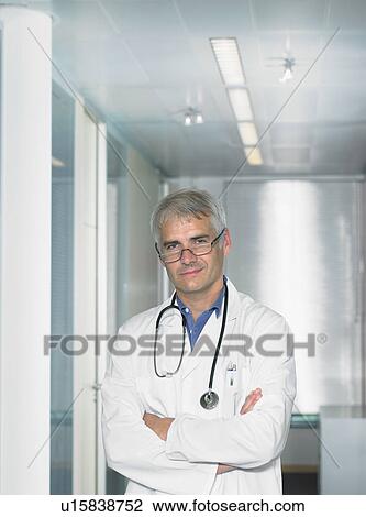 Stock Image - Portrait of mature male doctor in a lobby of a hospital.. Fotosearch