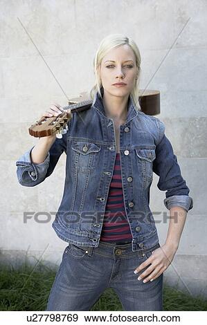 Woman standing holding a guitar. View Large Photo Image Stock Photo - Woman standing holding a guitar.. Fotosearch
