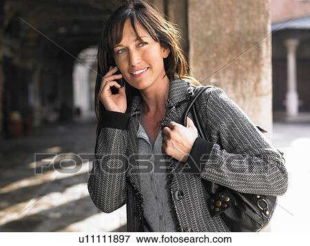 Stock Photo - Woman talking on mobile phone. Venice, Italy.. Fotosearch