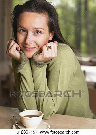 Woman with a mug at a table indoors smiling. View Large Photo Image Stock Photo - Woman with a mug at a table indoors smiling.. Fotosearch
