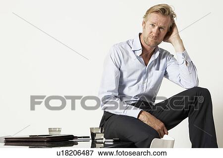 Young businessman seated on desk. View Large Photo Image Stock Photo - Young businessman seated on desk.. Fotosearch