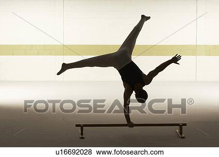 Male gymnast balancing on one hand on floor bar, rear view View Large Photo Image Stock Photo - Male gymnast balancing on one hand on floor bar, rear view. Fotosearch