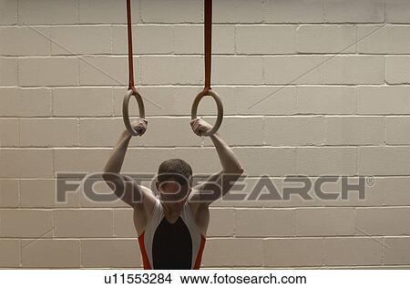 Male gymnast hanging from rings, looking down View Large Photo Image Picture - Male gymnast hanging from rings, looking down. Fotosearch
