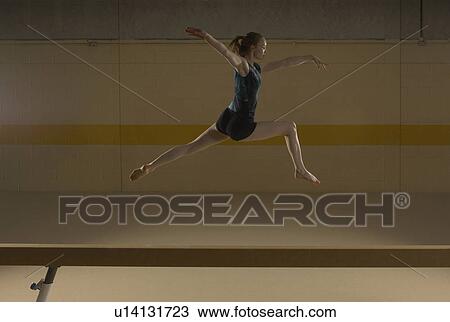 Teenage gymnast (16-18) leaping on balance beam View Large Photo Image Stock Image - Teenage gymnast (16-18) leaping on balance beam. Fotosearch