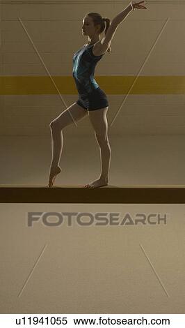 Stock Photography - Teenage gymnast (16-18) performing on balance beam. Fotosearch
