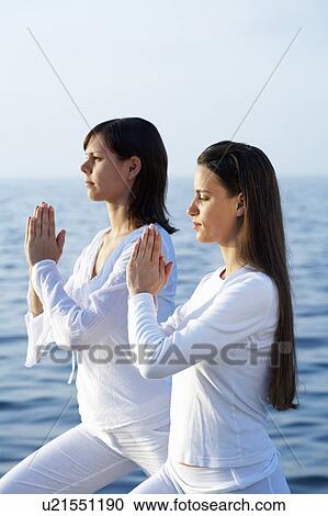 Two young women doing yoga by the sea. View Large Photo Image Stock Image - Two young women doing yoga by the sea.. Fotosearch