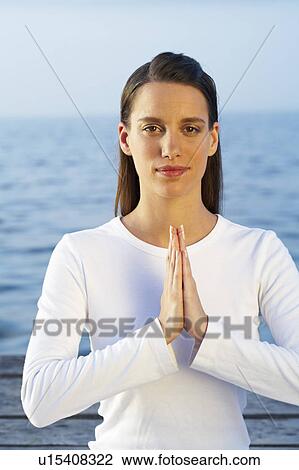 Stock Image - Young woman doing yoga on dock by the sea.. Fotosearch