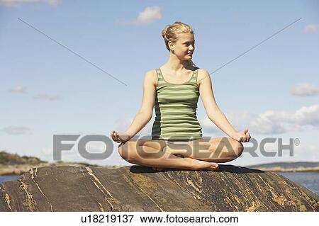 Stock Photo - Young Woman doing Yoga on rocks.. Fotosearch