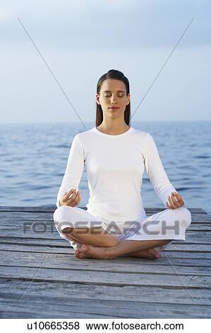 Young woman with eyes closed sitting cross legged on a dock. View Large Photo Image Stock Photo - Young woman with eyes closed sitting cross legged on a dock.. Fotosearch