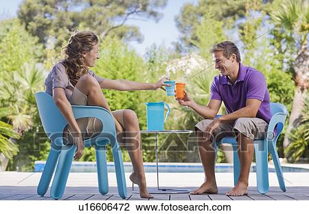 Couple on a wooden terrace by a pool View Large Photo Image Stock Image - Couple on a wooden terrace by a pool. Fotosearch