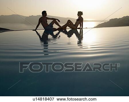 Stock Photo - Couple sitting on the edge of pool. Fotosearch