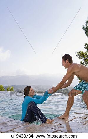 Picture - Man helping a woman out of a pool. Fotosearch