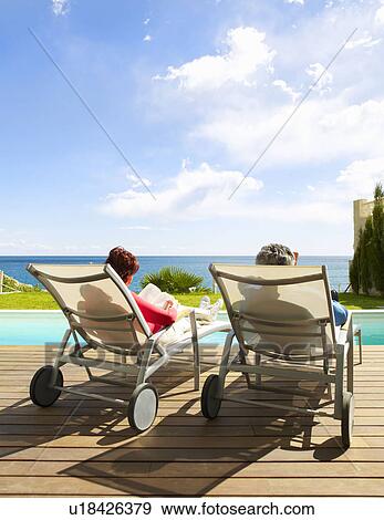 Mature couple relaxing by the pool View Large Photo Image Stock Photo - Mature couple relaxing by the pool. Fotosearch