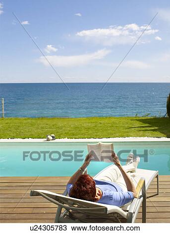 Stock Image - Mature woman relaxing on a deck chair. Fotosearch