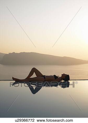 Woman laying on the edge of a pool View Large Photo Image Stock Image - Woman laying on the edge of a pool. Fotosearch
